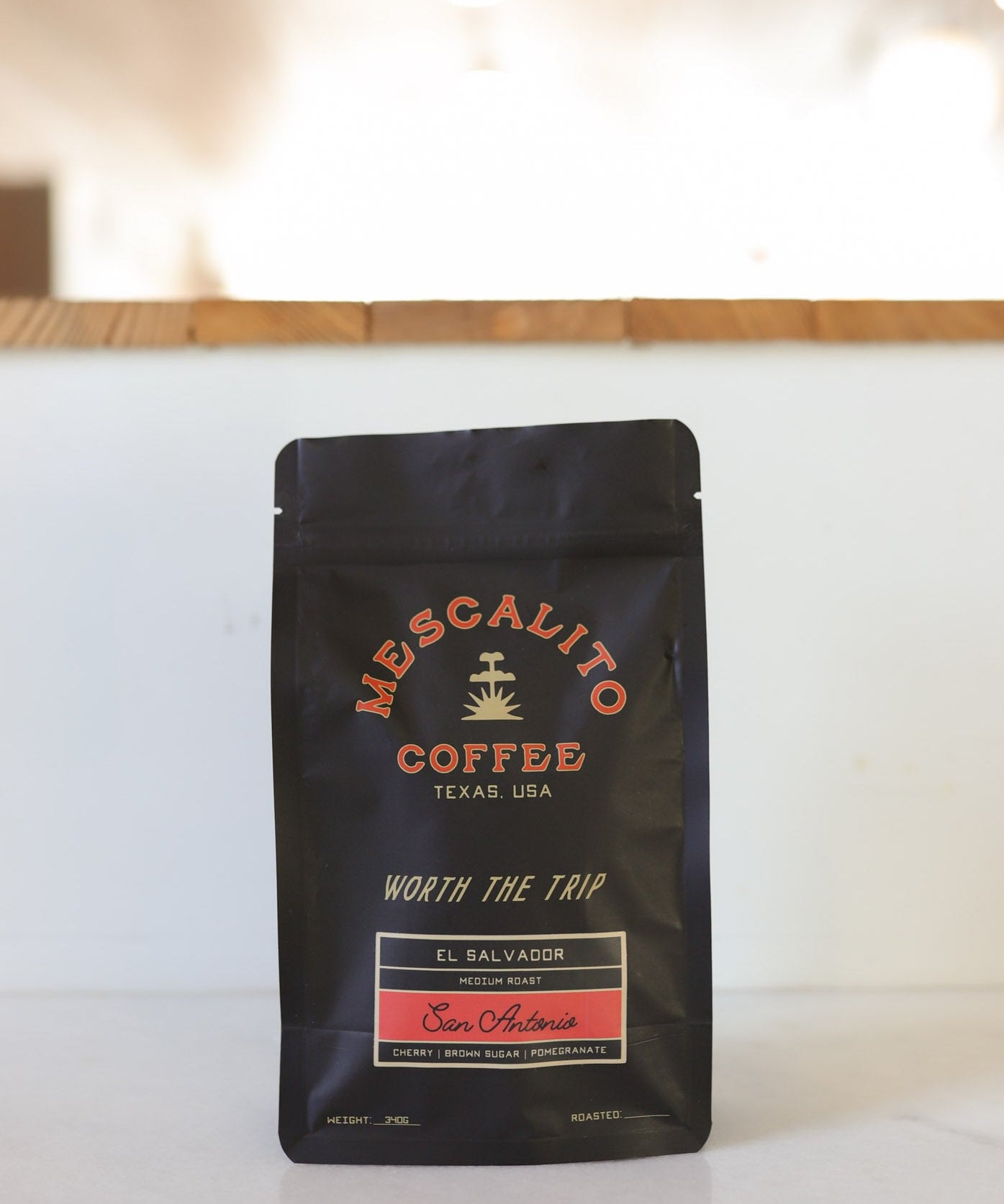 A black bag of Mescalito Coffee labeled "Blend Whole Coffee Beans | San Antonio" from Texas, USA, featuring Pacamara beans with anaerobic fermentation, sits on a white surface.