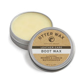 An open tin of Otter Wax Boot Wax displays the label and solid wax inside. The label highlights it as a leather protector made by Otter Wax, featuring beeswax and lanolin for natural waterproofing and leather care.