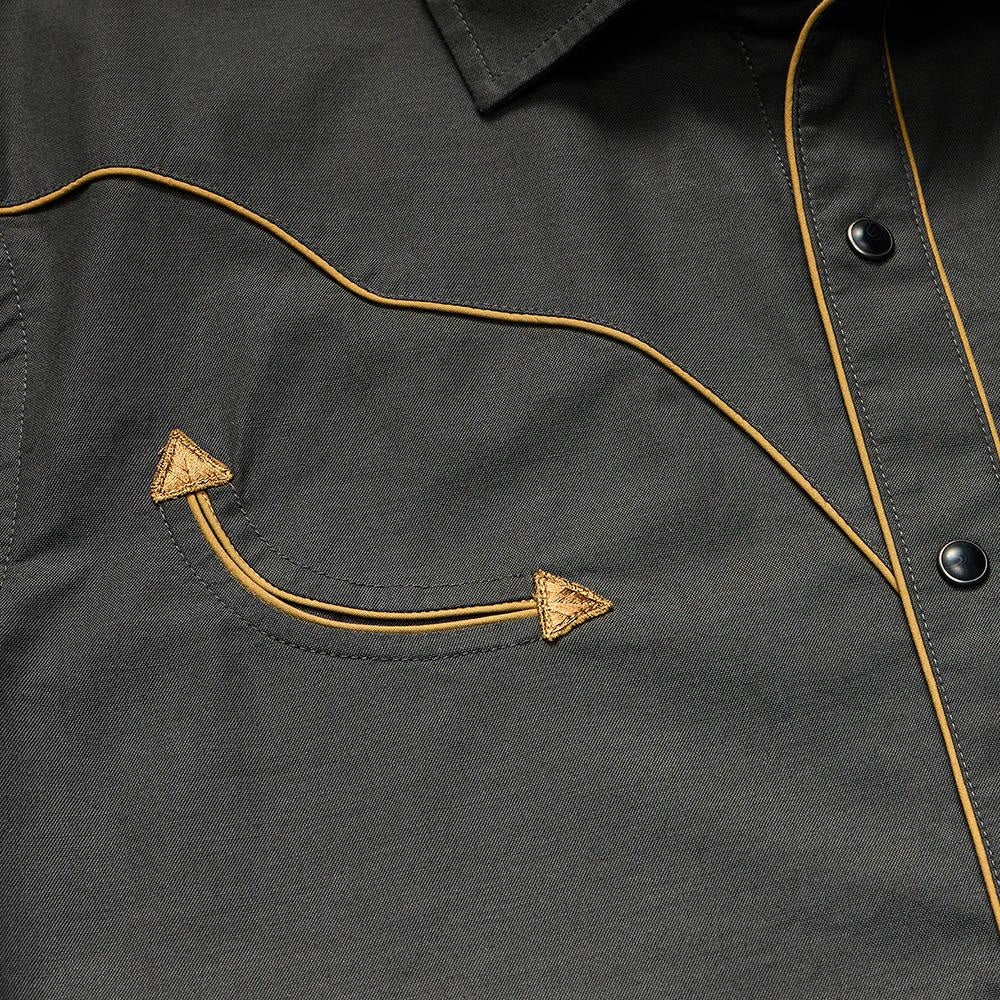 Close-up of the Broncbuster Snapshirt by Howler Brothers, featuring yellow piping, pearl snap buttons, and a pocket with decorative stitching and two triangular accents.