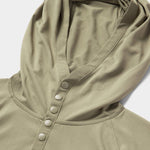 Close-up of the Duck Camp Bug Screen First Layer Hoodie in light olive green, featuring four snap buttons and a small embroidered logo on textured fabric—ideal for lightweight sun protection.