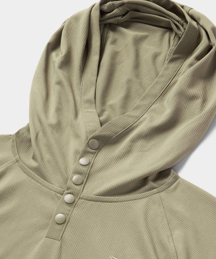 Close-up of the Duck Camp Bug Screen First Layer Hoodie in light olive green, featuring four snap buttons and a small embroidered logo on textured fabric—ideal for lightweight sun protection.