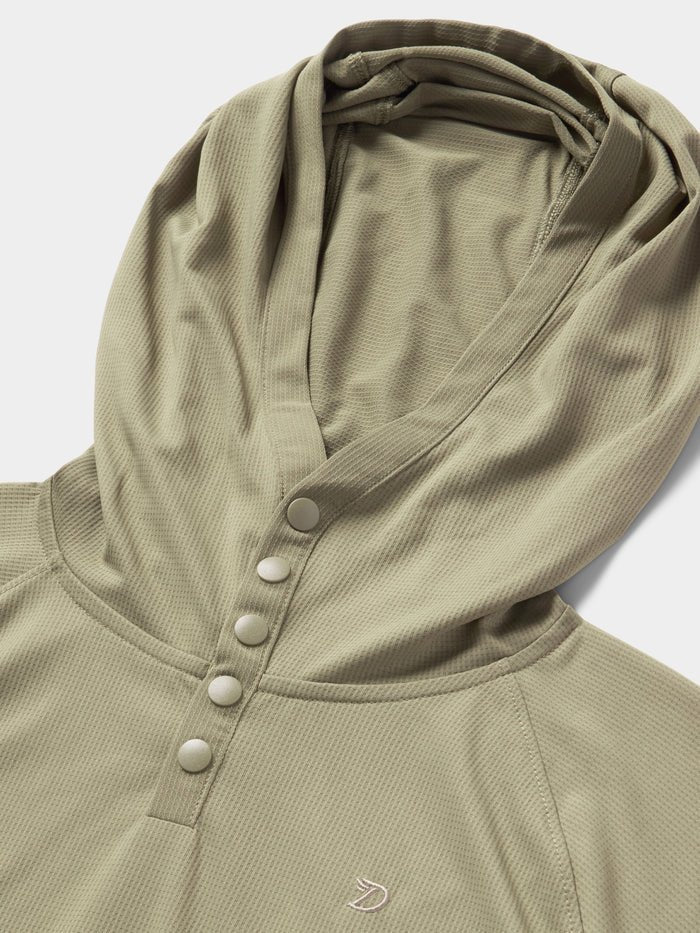 Close-up of the Duck Camp Bug Screen First Layer Hoodie in light olive green, featuring four snap buttons and a small embroidered logo on textured fabric—ideal for lightweight sun protection.