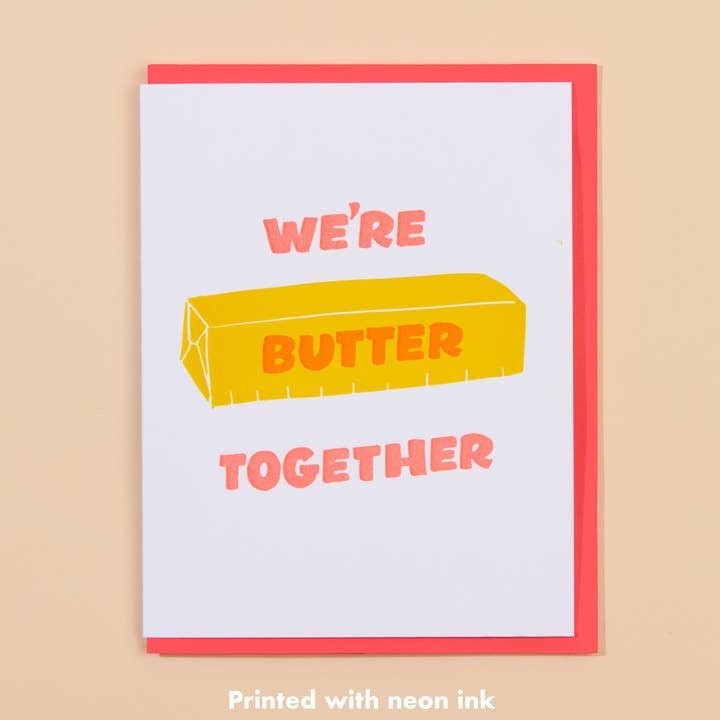 The Butter Together Card by And Here We Are features the message "WE'RE BUTTER TOGETHER" with a cute butter stick illustration, letterpress printed in neon ink on a white and pink love card.
