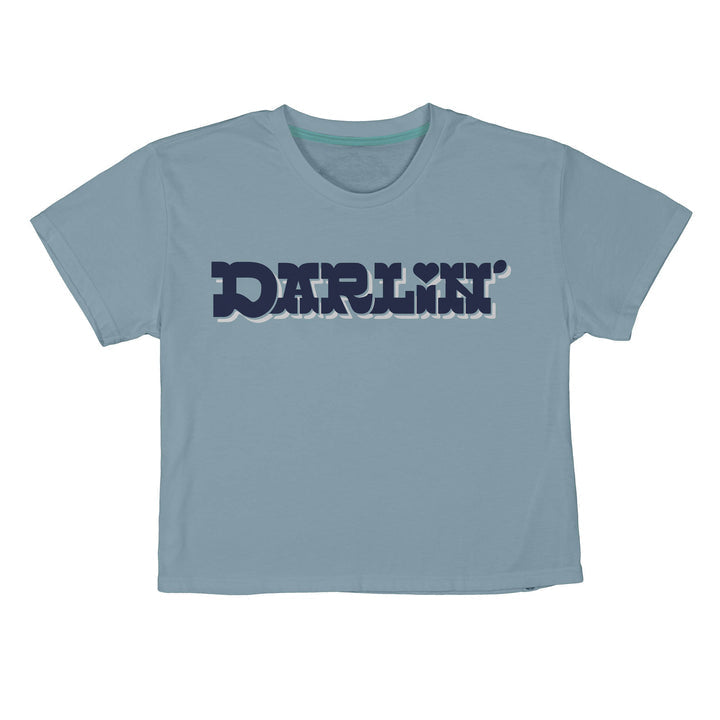 The Call Me Darlin' Boxy Tee by Sendero Provisions Co. features "DARLIN’" in bold, dark blue retro lettering with a heart over the “I”—a light blue shirt made for sparking friendly conversations and memorable introductions.