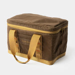 The Duck Camp Canvas Ammo Tote by Duck Camp is a rectangular, brown soft-sided cooler bag featuring yellow handles and a zippered top, displayed against a plain white background.