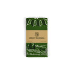 The Mollyjogger CCC Legacy Bandana is a folded green 100% cotton bandana with a nature-inspired white and dark green print, wrapped in a brown paper label celebrating the Civilian Conservation Corps.