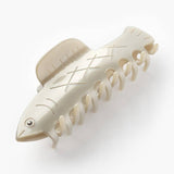 The Herring Claw by Winona Irene is a cream-colored cellulose acetate hair clip shaped like a fish, complete with fins, an eye, and scale details—an adorable accessory for any look.