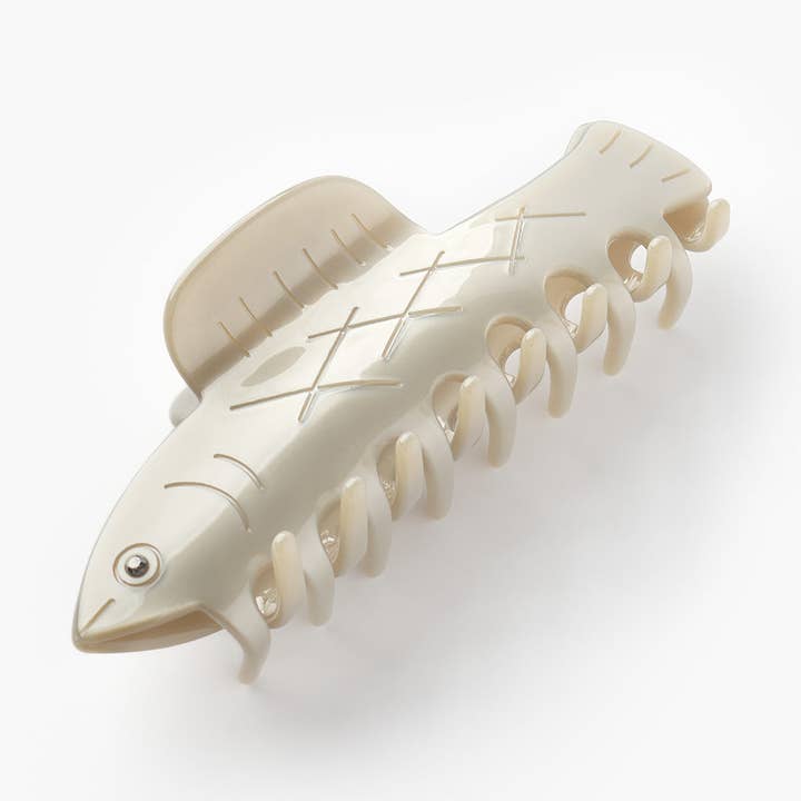 The Herring Claw by Winona Irene is a cream-colored cellulose acetate hair clip shaped like a fish, complete with fins, an eye, and scale details—an adorable accessory for any look.