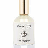 A clear glass perfume bottle with a gold cap, labeled "Chateau | Thin Wild Mercury" by Thin Wild Mercury, featuring a bell illustration and evoking the timeless charm of a vintage bungalow.