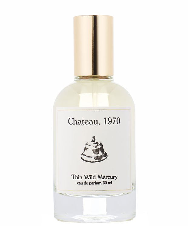 A clear glass perfume bottle with a gold cap, labeled "Chateau | Thin Wild Mercury" by Thin Wild Mercury, featuring a bell illustration and evoking the timeless charm of a vintage bungalow.