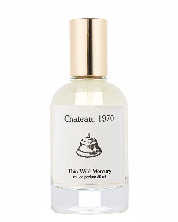 A clear glass perfume bottle with a gold cap, labeled "Chateau | Thin Wild Mercury" by Thin Wild Mercury, featuring a bell illustration and evoking the timeless charm of a vintage bungalow.