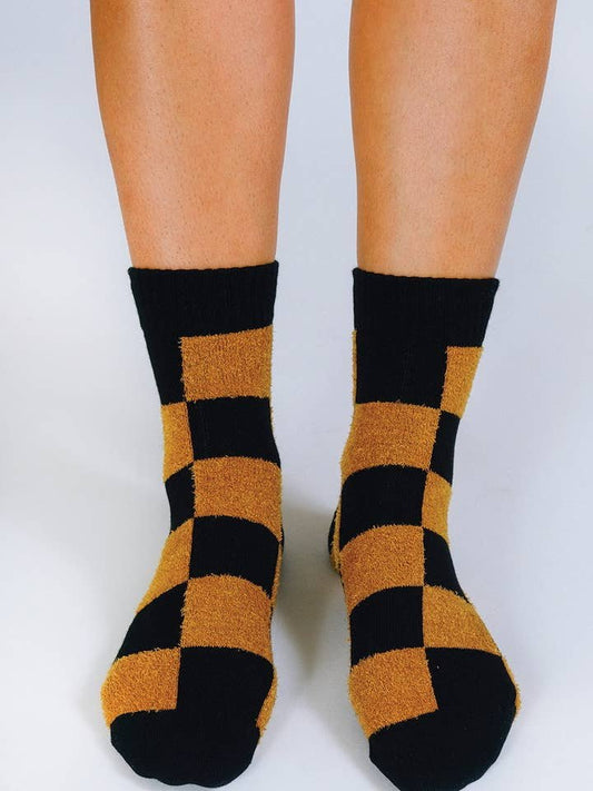 A pair of feet wearing Tailored Union Cheq Ankle Socks in black and yellow combed cotton against a plain white background.