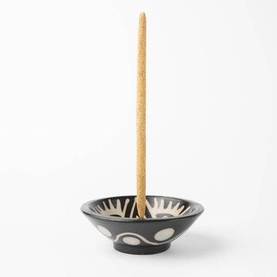 The Chulucanas Ceramic Incense Holder Modelo Clasico by Luna Sundara, handcrafted in Peru, features black ceramic with white abstract designs and holds a burning incense stick upright against a white background.