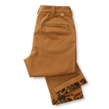 A pair of folded Duck Head Classic Fit Brushed Back Chino pants in brown, featuring a single back pocket and patterned lining peeking from the bottom cuffs.