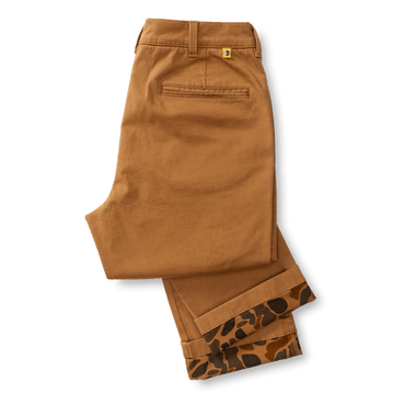 A pair of folded Duck Head Classic Fit Brushed Back Chino pants in brown, featuring a single back pocket and patterned lining peeking from the bottom cuffs.