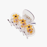 The Winona Irene Clear Acetate Hair Claw features delicate yellow floral designs, evoking the charm of a Thunbergia vine. Displayed on a clean white background, this translucent accessory adds a touch of elegance to your hairstyle.