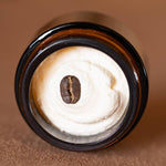 RANCH ROAST Coffee & Vanilla Infused Tallow Eye Cream by Cowboy & Co. comes in a brown glass jar with creamy white whipped tallow, topped with a single coffee bean.