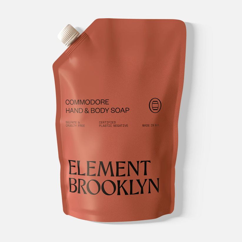 A rust-colored refill pouch labeled "Commodore Hand Soap" by Element Brooklyn, with a white cap and minimalist text, provides an aromatic hand washing experience with a distinctive scent.