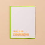 The Cooler/Hotter Birthday Card by And Here We Are features neon orange text on white letterpress, set on a green envelope with a peach background, displaying "AND HERE WE ARE" alongside other business details.