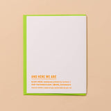 The Cooler/Hotter Birthday Card by And Here We Are features neon orange text on white letterpress, set on a green envelope with a peach background, displaying "AND HERE WE ARE" alongside other business details.