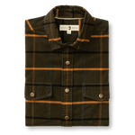 The Duck Head Corduroy Plaid Snap Shirt is a folded, long-sleeve workwear shirt in cotton corduroy with a dark green, orange, and blue plaid pattern and flap pockets.