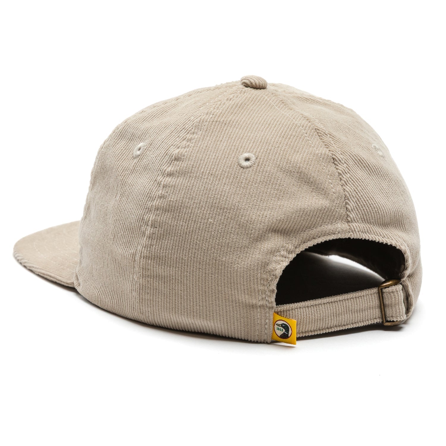 The Duck Head Corduroy Unstructured 5-Panel Hat is shown from the back, featuring beige cotton corduroy, an adjustable buckle, and a small yellow tag.