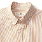 A close-up of the Duck Head Cotton Oxford Sport Shirt Collins Stripe, featuring beige and white stripes, a button-down collar, and a visible brand label inside the neckline.