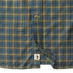 Close-up of Duck Head’s Cotton Wool Sport Shirt featuring blue, green, and brown plaid, a button detail, and a small tag with duck logo near the hem.