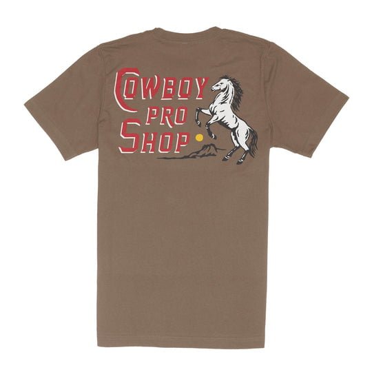 The Cowboy Pro Shop T-Shirt by Sendero Provisions Co. is a brown tee with "COWBOY PRO SHOP" in red and white and a rearing horse graphic on the back, reflecting Mississippi western style with bold, standout energy.