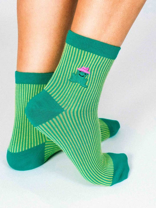 Person wears Cowgirl Frog Ribbed Ankle Sock by Hannah Packer for Tailored Union—green and yellow striped ankle socks with solid green toes, heels, cuffs, and an embroidered frog with a pink crown, crafted from premium combed cotton.