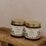 Two jars of Cowboy & Co.'s COWGIRL Vanilla Infused Tallow sit on a rustic wooden stool against a neutral background—ideal for sensitive skin.