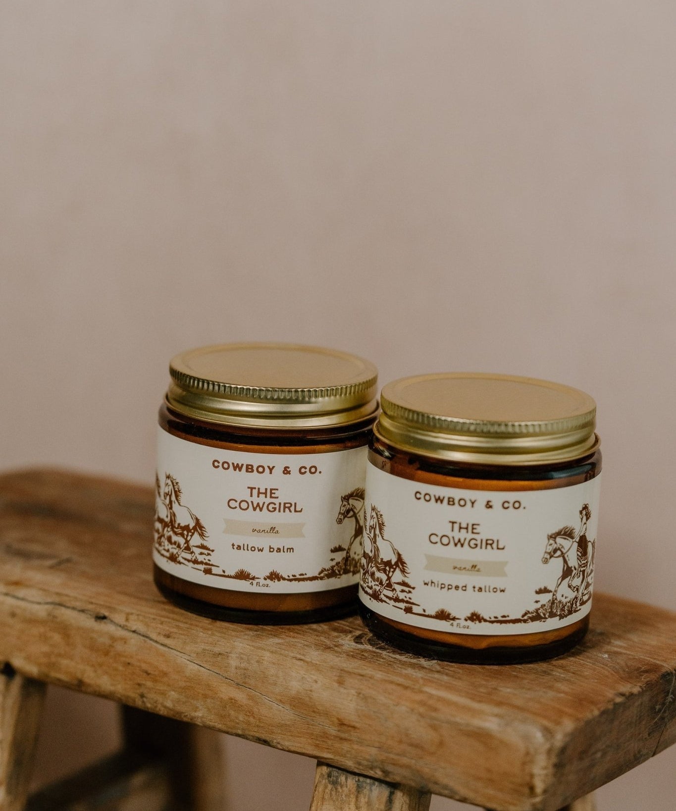 Two jars of Cowboy & Co.'s COWGIRL Vanilla Infused Tallow sit on a rustic wooden stool against a neutral background—ideal for sensitive skin.