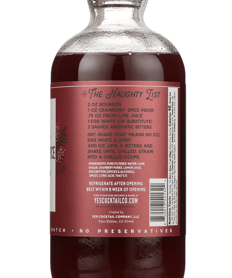 A glass bottle of Cranberry Spice by Yes Cocktail Co. features a label with cocktail recipe instructions and a barcode on the back.