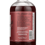 A glass bottle of Cranberry Spice by Yes Cocktail Co. features a label with cocktail recipe instructions and a barcode on the back.