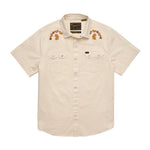 The Howler Brothers Crosscut Deluxe Snapshirt | Fowl Play is a short-sleeve, beige pearl snap shirt featuring front pockets and custom floral embroidery on the shoulders.