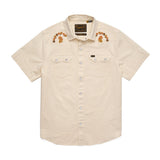 The Howler Brothers Crosscut Deluxe Snapshirt | Fowl Play is a short-sleeve, beige pearl snap shirt featuring front pockets and custom floral embroidery on the shoulders.