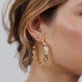 Close-up of a woman's ear wearing JaxKelly Daisy Chain Hoop Earrings—a floral design in gold, tarnish-free and perfect for everyday wear.
