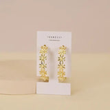 A pair of JaxKelly Daisy Chain Hoop Earrings, tarnish-free jewelry, shown on a white JaxKelly card against a neutral background.