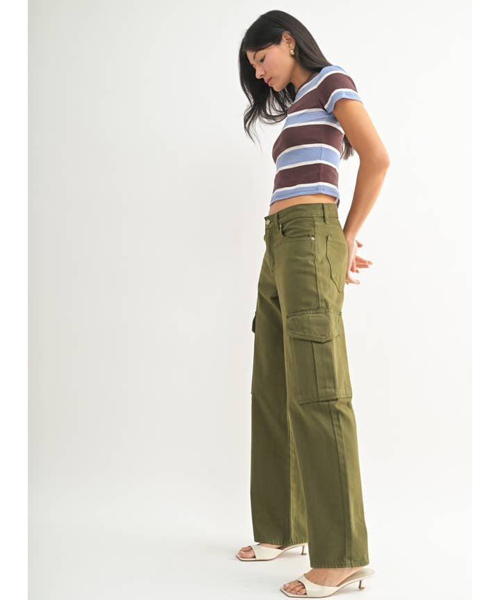 Woman in profile wears a striped crop top, JBD Dark Olive Cargo high-rise pants, and white heeled sandals against a plain white background.