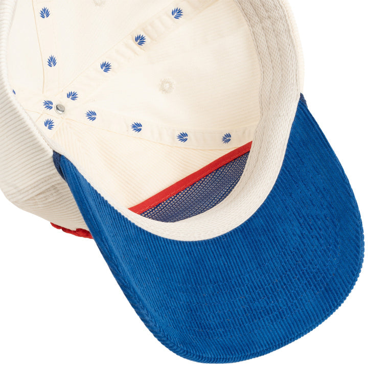 A close-up of the Darlin' Hat by Sendero Provisions Co. shows its 5-panel corduroy snapback, blue corduroy brim, cream interior with small blue designs, and a red mesh section near the front.