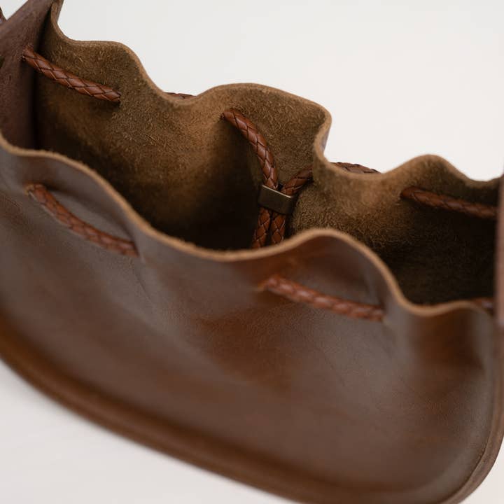 The Stash Joi Bag in Chestnut Distressed is a Japanese-inspired open brown leather drawstring handbag, shown from above on a plain background, featuring braided leather drawstrings, visible inner compartments, refined detailing, and practical elegance.