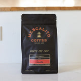 A black bag of Mescalito Coffee’s Decaf Whole Coffee Beans | Starlite features Colombian sugarcane decaf with tasting notes of caramel, mandarin orange, and cinnamon in a smooth medium roast.