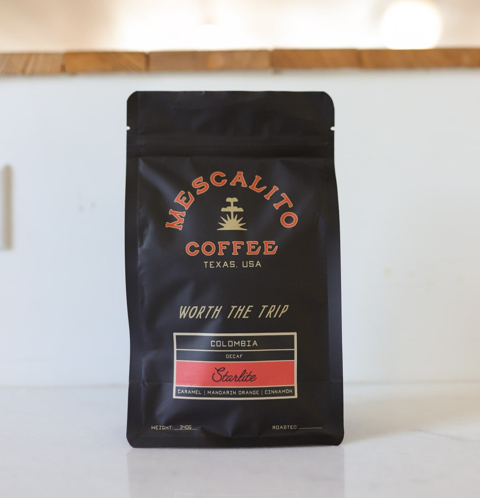 A black bag of Mescalito Coffee’s Decaf Whole Coffee Beans | Starlite features Colombian sugarcane decaf with tasting notes of caramel, mandarin orange, and cinnamon in a smooth medium roast.