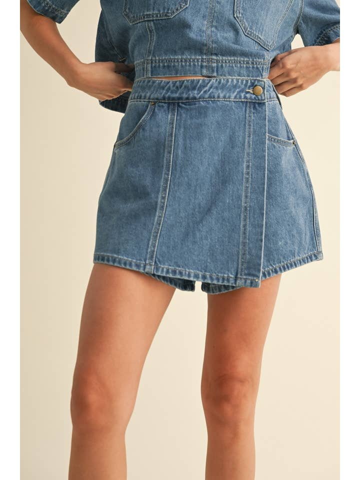 Model wears the Miou Muse Denim Skort, featuring front buttons and pockets—shown from waist to mid-thigh—a versatile women's piece that pairs perfectly with a matching top.