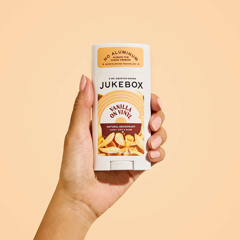 A hand holds Jukebox Deodorant | Vanilla on Vinyl with a beige background, offering 72-hour odor protection with Odor Blocking Technology.