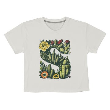 Ultra-soft and made from organic cotton, the Sendero Provisions Co. Desert Mark Boxy Tee features a white short sleeve design with an illustrated "S" formed by green succulents and colorful flowers.