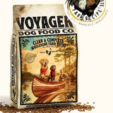 Voyager Dog Food Co. Clean & Complete Wholesome Farm Recipe is a veterinarian-created dog food, ideal for dogs with copper storage disease. Packaging shows two dogs in a canoe, scattered kibble, and the Voyager Dog Food Co. rooster logo.