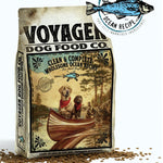Voyager Dog Food Co.'s Dog Food, crafted for optimal health, shows dogs in a canoe with scattered kibble and a "Clean & Complete Ocean Recipe" label on the packaging.
