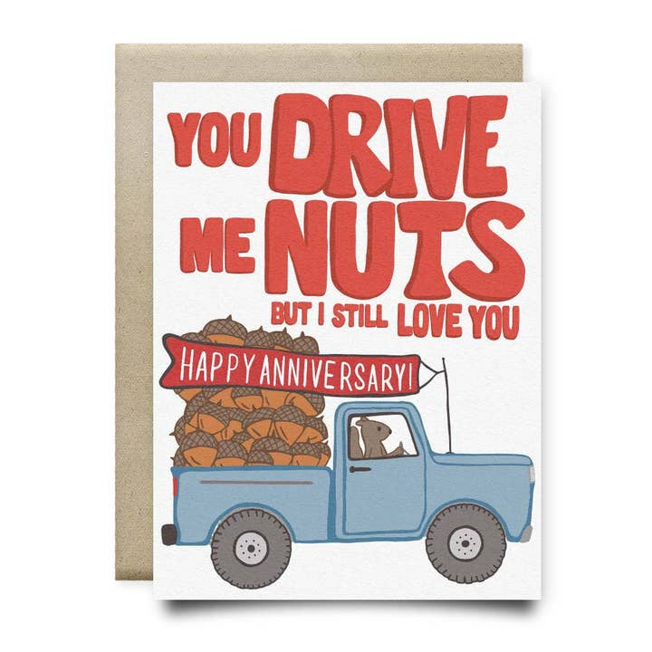 The Anvil Cards "Drive Me Nuts Anniversary Card" features a hand-drawn blue truck driven by a dog with nuts in the back, red "You drive me nuts but I still love you" text, and a "Happy Anniversary!" banner on quality linen paper.