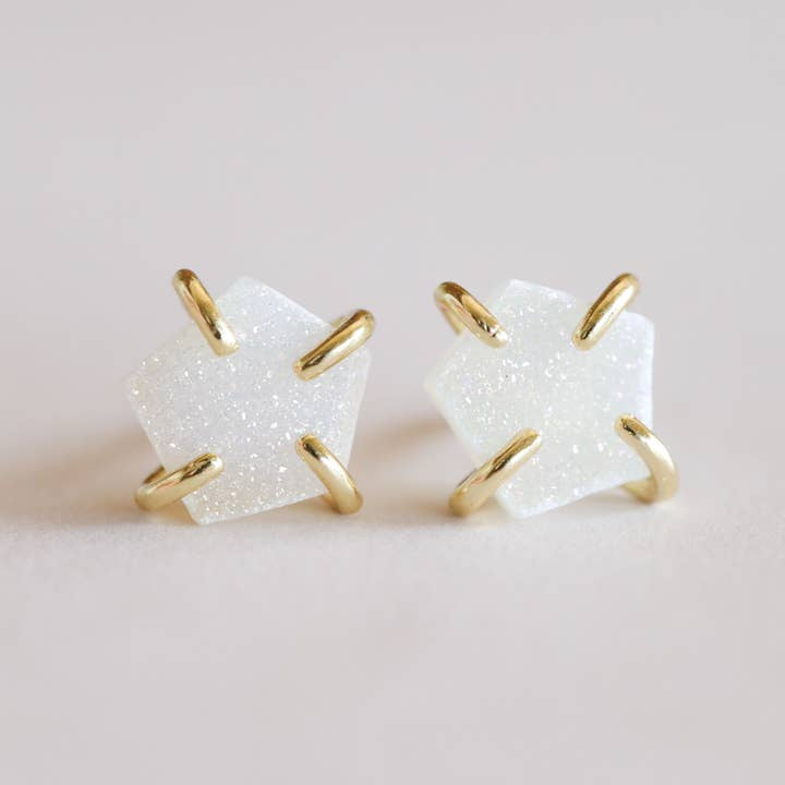 The Druzy Prong - White - Gold Earrings by JaxKelly feature glittery white druzy stones in pentagon shapes, set in gold prongs, shown against a neutral background.
